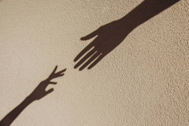 istock Shadows of hands reaching each other on the wall. 2163374939