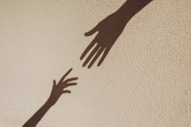 istock Shadows of hands reaching each other on the wall. 2163374940