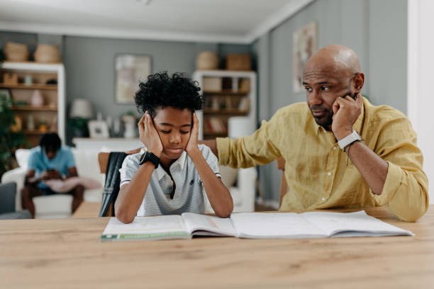 istock Boy covers ears, parent encourages focus on homework. 2163376134