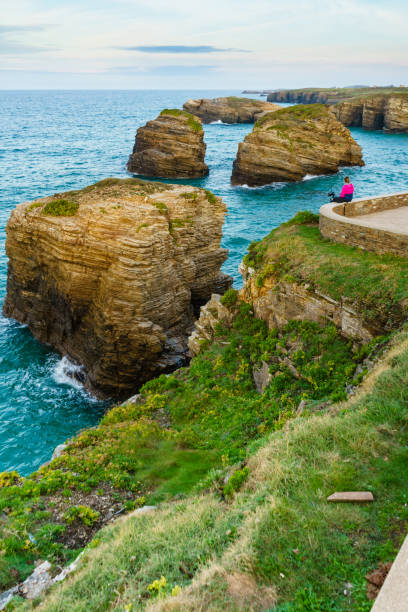 Tourist woman enjoying sea coast landscape, visiting Cathedral Beach in Galicia Spain. Playa de las Catedrales, As Catedrais in Ribadeo, province of Lugo.