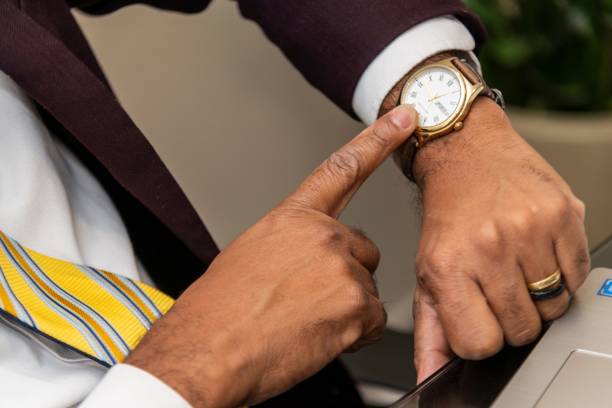 A Businessman checking the time on his wristwatch while working on a laptop