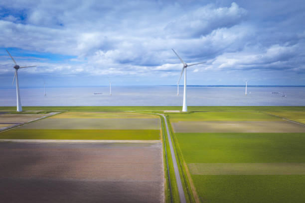 Rows of wind turbines on the IJsselmeer shore in the Noordoostpolder in Flevoland, The Netherlands, during springtime seen from above. The Noordoostpolder is a polder in the former Zuiderzee designed initially to create more land for farming.