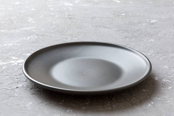 istock Perspective view of empty black plate on cement background. Empty space for your design 2163389589