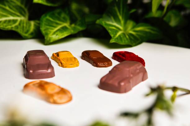 A variety of chocolate car treats in different colors are arranged on a white surface.