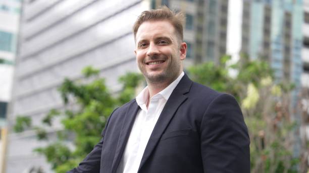istock Smart caucasian business man looking at camera while standing at rooftop. Urbane 2163393935
