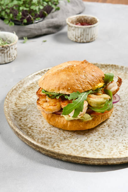 istock Gourmet Shrimp Burger with Guacamole and Fresh Arugula on Rustic Plate 2163397046