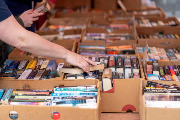 Reaching for a book Dordrecht, Netherlands - July 7, 2024: Visitors explore second-hand books at the annual book market in Dordrecht, 350 stalls throughout the city centre, where booksellers offer their best books. book display stock pictures, royalty-free photos & images