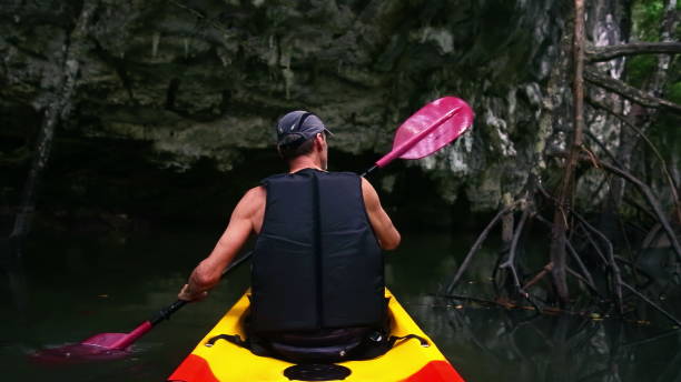 istock Man navigates kayak passing route with tree branches 2163406950