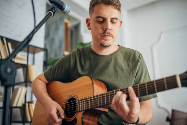 istock Man playing guitar seated with a microphone stand. 2163410716
