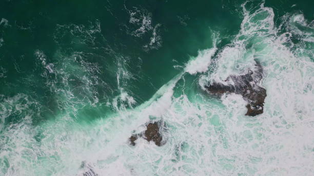 istock Powerful ocean crashing rocks top view. Turquoise waves hitting dangerous cliffs 2163412399