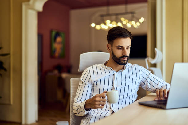 istock A busy freelance man working with a coffee in his hands, using a laptop. 2163415433