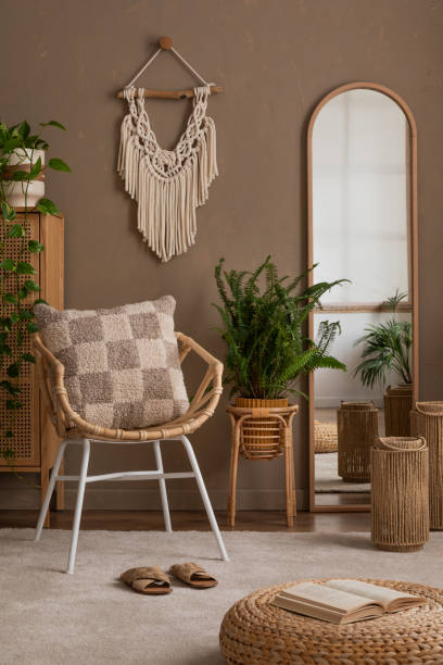 istock Creative composition of bedroom interior with mirror, chess board print pillow, plaid, plants in flowerpots, macrame, rattan sideboard, brown wall and personal accessories. Home decor. Template. 2163415584