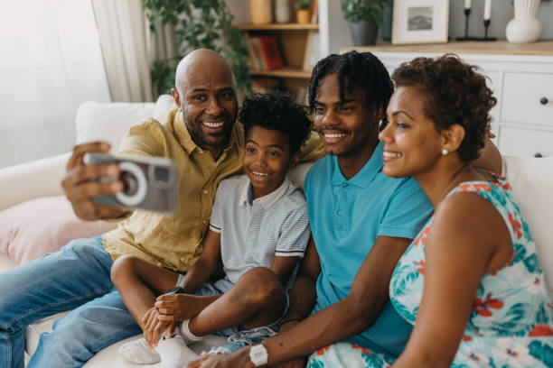 Smiling family taking a selfie together, sitting on sofa