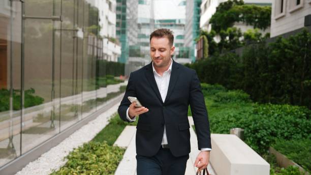 istock Businessman walking at park while talking to manager by using phone. Urbane. 2163416739