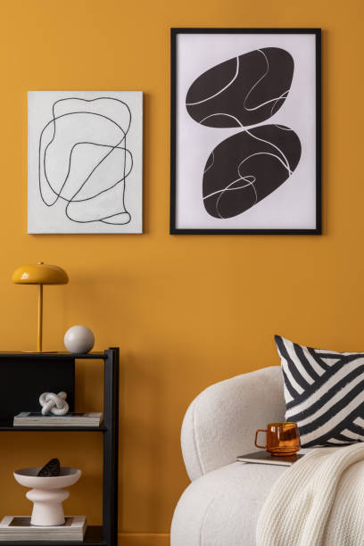 istock Warm and cozy living room interior with  mock up poster frame, boucle sofa, patterned pillows, white plaid, black rack, marble lamp, yellow wall, books and personal accessories. Home decor. Template. 2163417707