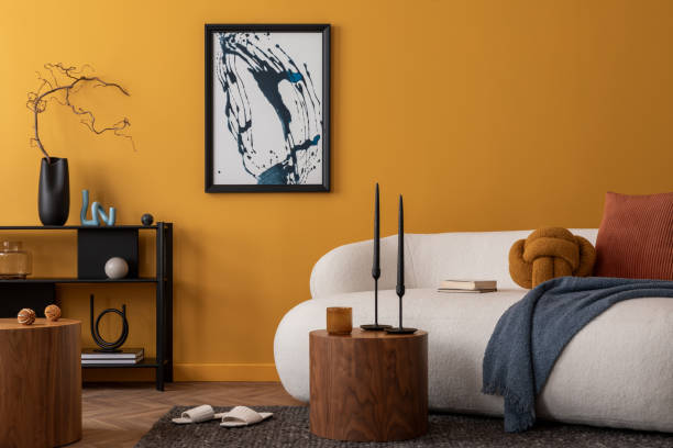 istock Interior design of cozy living room with mock up poster frame, boucle sofa, patterned pillows, black rack, wooden coffee table, vase with flowers and personal accessories. Home decor. Template. 2163417818