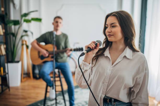 istock Confident singer with guitarist performing indoors, smiling 2163418528
