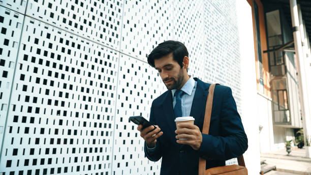 istock Professional manager looking at mobile phone while walking at street. Exultant. 2163421022