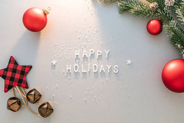 White letters spelling Happy Holidays surrounded by red ornaments, a plaid star, bells, and pine branches.