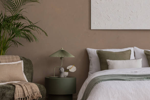 istock Creative composition of bedroom interior with mock up poster frame, braided pouf, plants, gray armchair, stylish lamp, round coffee table, braided rug and personal accessories. Home decor. Template. 2163422937