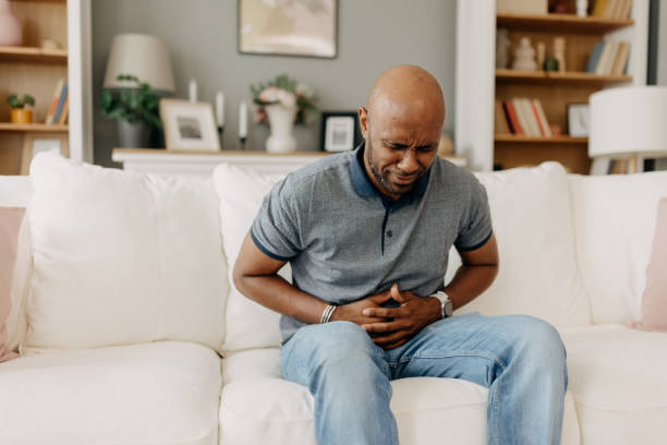 istock Man suffering from stomach pain on white couch indoors 2163434783