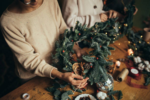 istock Happy women making Christmas wreath using natural pine branches and festive decorations. 2163437212