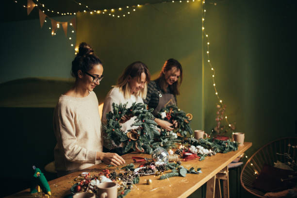 istock Happy women making Christmas wreath using natural pine branches and festive decorations. 2163437214