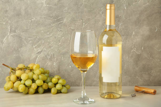 istock Bottle and glass with white wine with grape on grey background. 2163437915