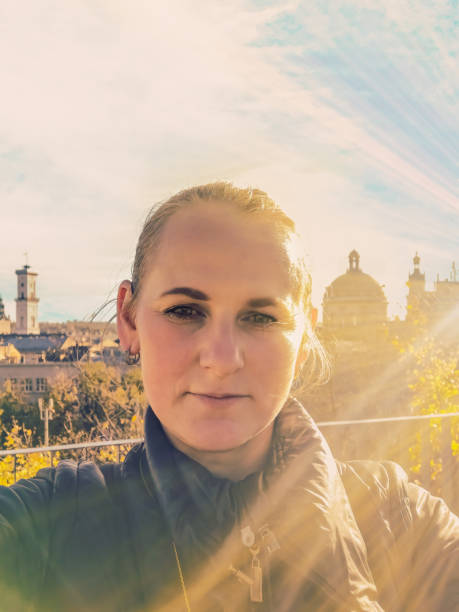 Lviv Beauty: Vertical Woman Selfie in Autumn Sun Rays, Ukraine. Old Town Panorama Adds Charm to Portrait. Ideal for Travel and Lifestyle Publications