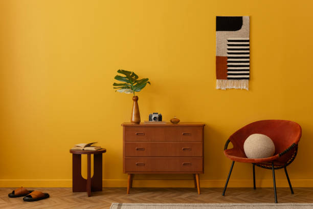 istock Minimalist composition on vintage living room interior with patterned killim rug, red armchair, stylish wooden sideboard, burgund stool, yellow wall and personal accessories. Home decor. Template. 2163446131