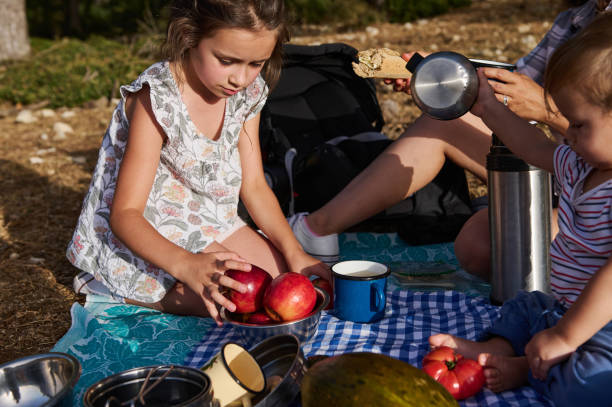 Children having a picnic with apples and snacks outdoors on a sunny day