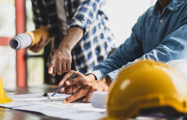 istock Brainstorming group of architects and engineers discuss building blueprint design on laptop and construction project planning on wooden table in office. 2163457529