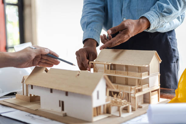 istock Colleague male architects in office discussing construction project. Young man working together on new building model. Engineers and architects working together to plan a house building project. 2163457558
