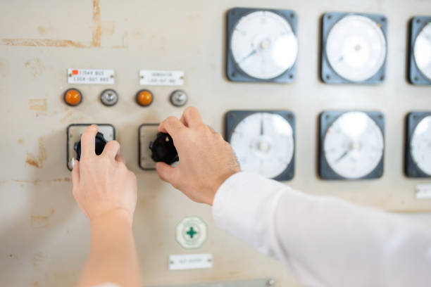 istock control and rotate Pressing a switch control button on a circuit board from the hands of a male and female engineer in the workshop of a power plant, energy industry where they work together. 2163458854