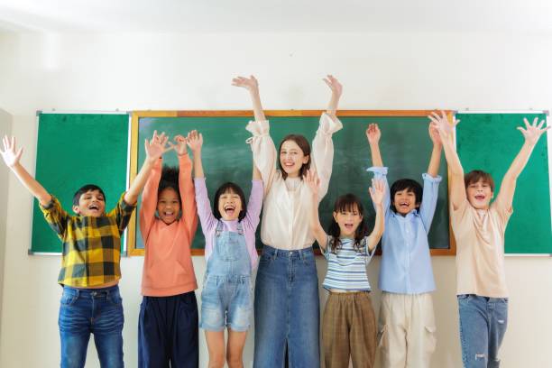 istock Happy teacher and students celebrating success in the classroom. 2163461204