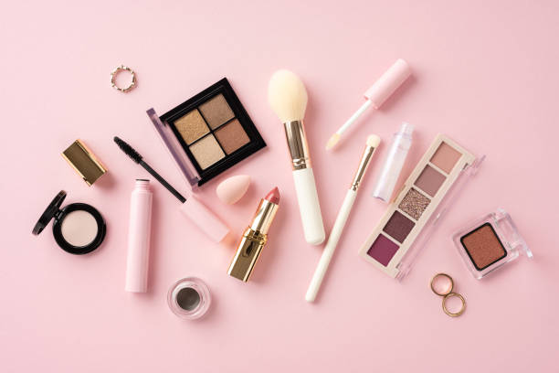 istock Various makeup items such as brushes, eyeshadow, lipstick, and mascara arranged on a pink background 2163467580