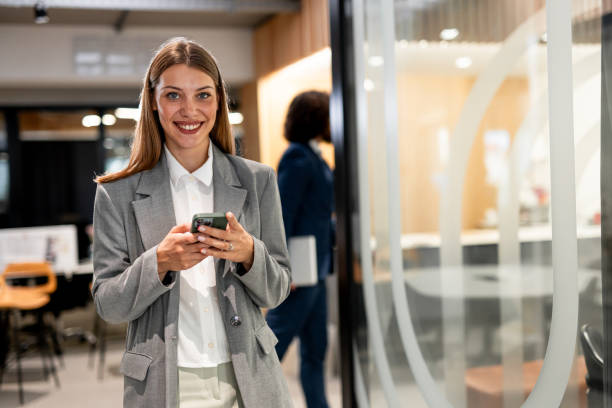 istock Smiling businesswoman using phone in office 2163467641