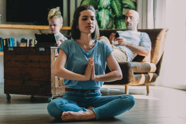 istock Young mother practicing yoga meditation at home while family rel 2163472444