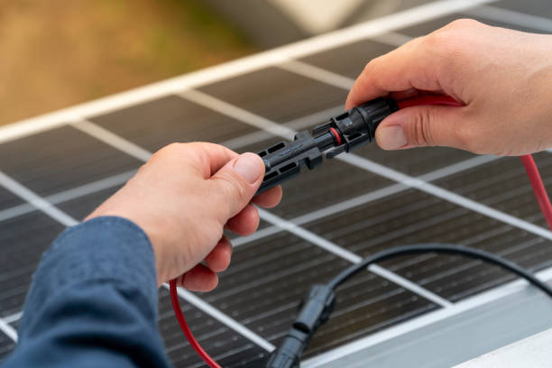 istock Close up of technician's hands connecting mc4 connectors over the solar panel. 2163473341