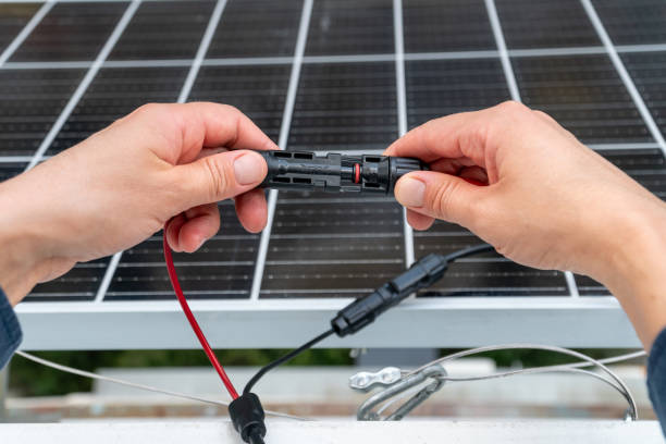 istock Close up of technician's hands connecting mc4 connectors over the solar panel. 2163473639