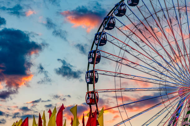West Allis, WI, USA - August 12, 2023: A colorful sunset falls behind the Ferris Wheel at the Wisconsin State Fair