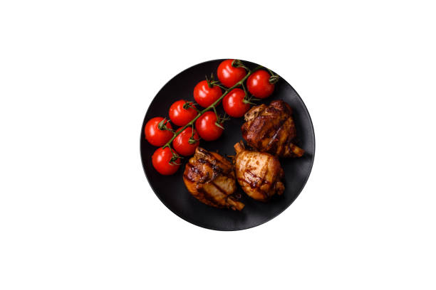 Delicious grilled chicken legs with spices and herbs in teriyaki sauce on a dark concrete background