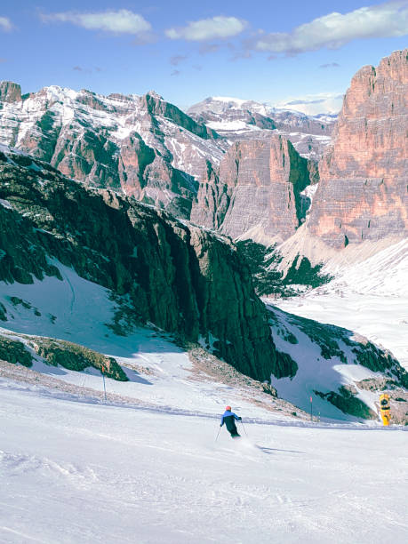 Skier skiing downhill in high mountains during sunny day.