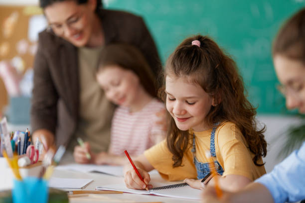 istock Happy kids and teacher at school 2163479930