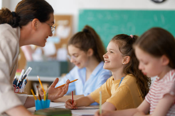 istock Happy kids and teacher at school 2163480008