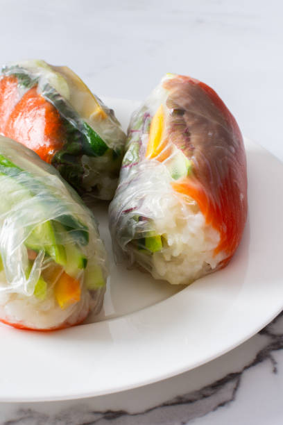These traditional Vietnamese spring rolls feature rice paper filled with lettuce, salmon, carrots, and cucumber, served with fish sauce, offering a light and flavorful appetizer