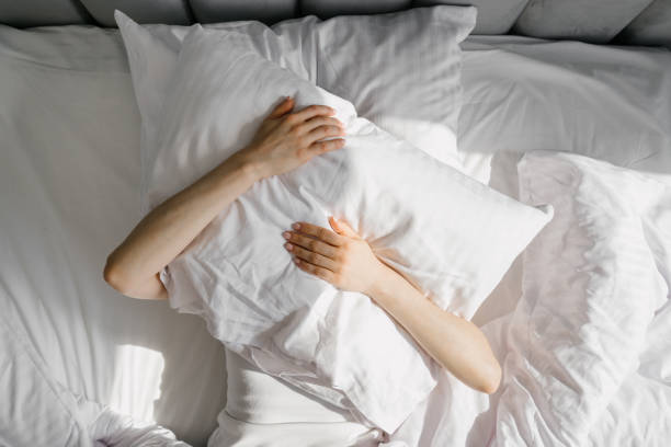 istock Female cover her head with cushion suffers from insomnia need sleeping pills 2163485123