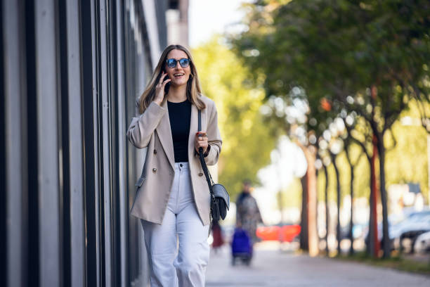 istock Pretty young woman using her smartphone while walking in the street 2163485641