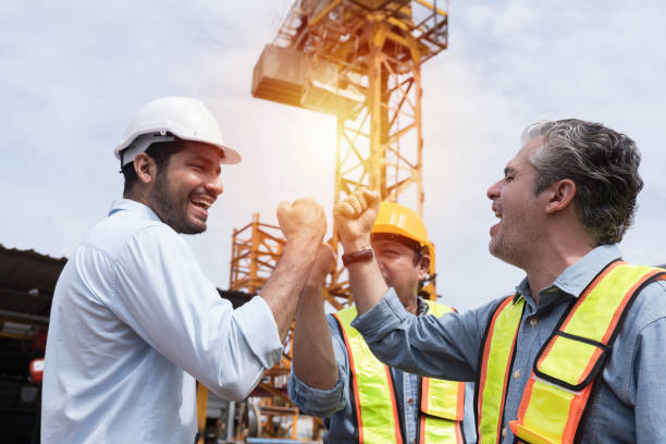 istock Team of male engineer construction standing and raise hands together at construction site. Group of male construction builder working at construction site. Unity and teamwork concept 2163485643
