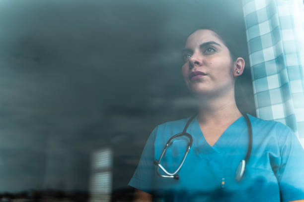 istock Female nurse contemplating looking through window 2163493478